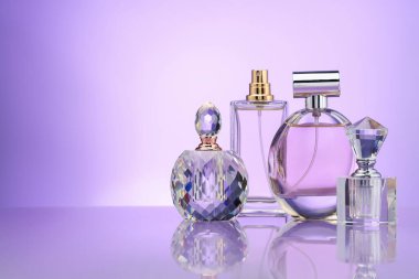 Ayna yüzeyindeki parfüm şişeleri menekşe gradyan arkaplan, metin için boşluk