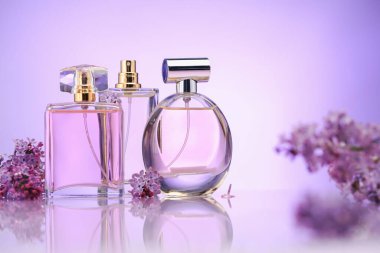 Ayna yüzeyindeki parfüm şişeleri ve leylak çiçekleri menekşe eğimli arka plan, seçici odak