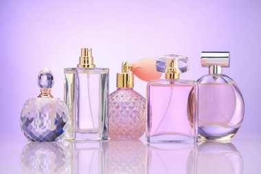 Ayna yüzeyinde menekşe eğimli arka plana karşı parfüm şişeleri