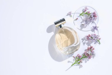 Bir şişe parfüm ve beyaz arka planda güzel leylak çiçekleri. Metin için boşluk