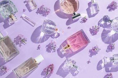 Lüks parfümler ve açık mor arka planda güzel leylak çiçekleri.