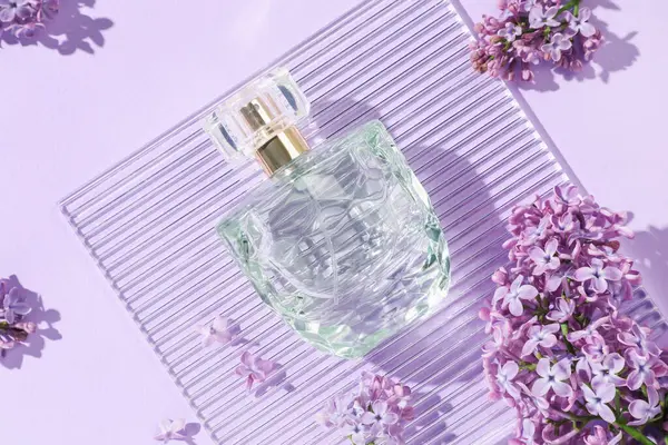 Bir şişe parfüm ve açık mor arka planda güzel leylak çiçekleri.