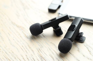 Lavalier mikrofonlar ve ahşap masada kablosuz alıcısı olan akıllı telefon.