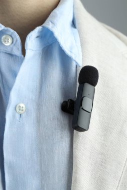 Takım elbisesine mikrofon takmış bir adam, yakın plan.