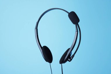 Açık mavi arka planda mikrofonlu kulaklık.