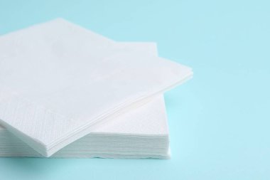 Açık mavi arkaplanda tek kullanımlık kağıt mendil yığını, yakın plan
