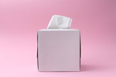 Pembe arka planda kağıt mendilli bir kutu.