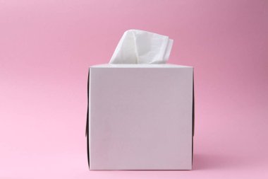 Pembe arka planda kağıt mendilli bir kutu.