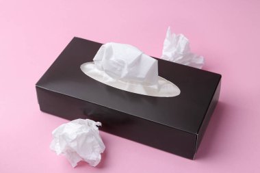 Kağıt mendilli kutu ve pembe arka planda buruşuk mendiller, yakın plan.
