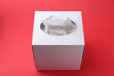 Kırmızı arkaplanda kağıt mendilli kutu, yakın plan