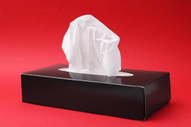 Kırmızı arkaplanda kağıt mendilli kutu, yakın plan