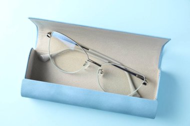 Açık mavi arka planda şık gözlüklü çanta, üst görünüm