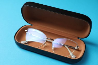 Açık mavi arka planda şık gözlüklü çanta, yakın plan