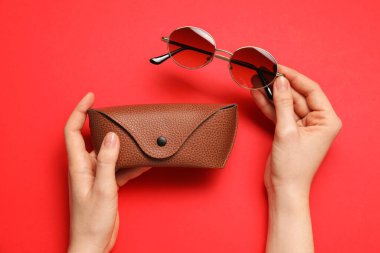Güneş gözlüklü kadın ve kırmızı arka planda çanta, üst görünüm