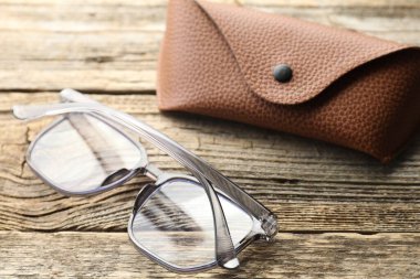 Şık gözlükler ve çanta ahşap masada, yakın plan.