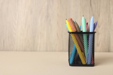 Bej masadaki tükenmez kalemler ahşap arka planda, yakın plan. Metin için boşluk