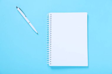 Açık mavi arkaplanda düz bir defter ve kalem var.
