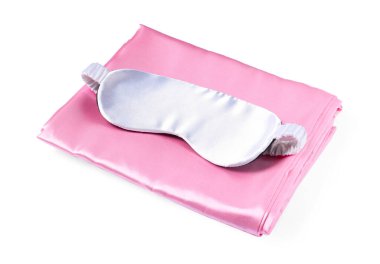 Beyaz arka planda ipek çarşaflar ve uyku maskesi.