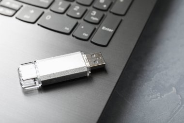 Gri desenli masadaki Usb flash diski ve laptop, yakın plan.