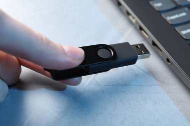 Gri desenli masadaki dizüstü bilgisayara bir kadın yerleştiriyor. Yakın plan.