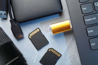 Dizüstü bilgisayara, SD hafıza kartlarına, harici sabit diske ve gri dokuma tablosundaki kamera lensine bağlı flaş bellek, düz konum