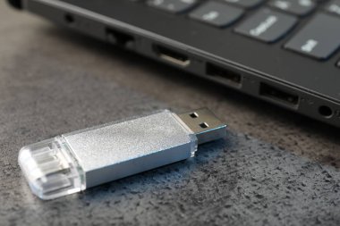 USB flaş bellek ve laptop koyu gri masada, yakın plan
