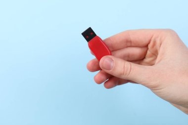 Flaş belleği açık mavi arka planda tutan kadın, yakın plan. Metin için boşluk