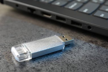USB flaş bellek ve laptop koyu gri masada, yakın plan