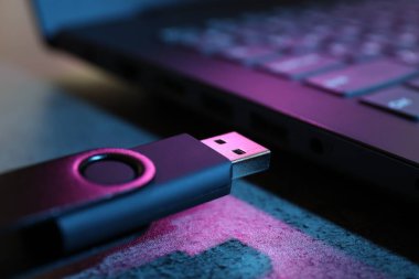 USB flaş bellek ve laptop koyu gri masada, yakın plan