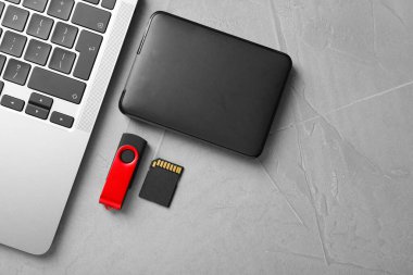 Flaş bellek, hafıza kartı, harici hard disk ve açık gri masadaki dizüstü bilgisayar, düz konum. Metin için boşluk