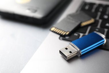 Flaş bellek, SD hafıza kartları, harici hard disk ve açık gri masadaki laptop, yakın plan. Metin için boşluk