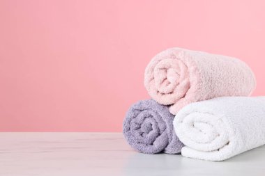 Açık mermer masa üzerindeki temiz havlular pembe arkaplana karşı, metin için boşluk