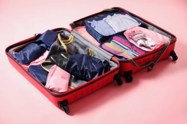 Pembe arka planda paketleme küpleri olan bavulu aç