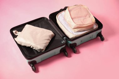 Pembe arka planda paketleme küpleri olan bavulu aç