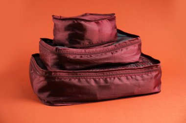 Parlak turuncu arka planda giysileri olan küpleri paketlemek