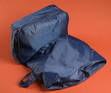 Parlak turuncu arka planda giysileri olan küpleri paketlemek, yakın plan