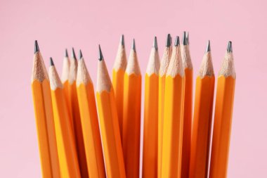 Pembe arka planda keskin grafit kalemler, yakın plan.