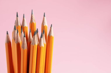 Pembe arka planda keskin grafit kalemler, yakın plan. Metin için boşluk