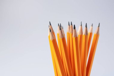 Açık gri arka planda keskin grafit kalemler, yakın plan. Metin için boşluk