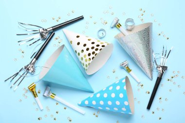 Açık mavi arka planda parti şapkaları ve konfetileri ile düz konum