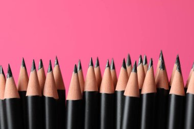 Pembe arka planda birçok keskin grafit kalem, yakın plan. Metin için boşluk