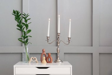 Işık duvarının yanındaki çekmecelerde yanan mumlar ve dekorlarla süslü zarif bir şamdan.