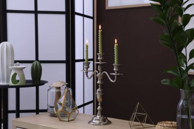 Kahverengi duvarın yanında yanan mumlar ve dekorlarla süslü zarif bir şamdan.