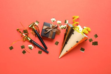 Güzel parti şapkası ve kırmızı arka planda diğer şenlikli dekorlar, düz yatış.