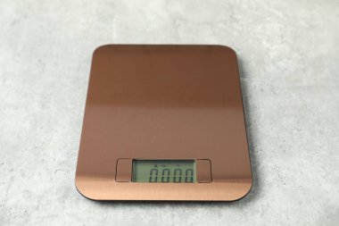 Gri masadaki modern elektronik mutfak terazisi, yakın plan.