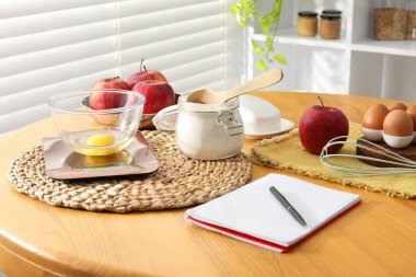 Elektronik mutfak ölçeği, ürünler ve ahşap masa üzerindeki kırtasiye.