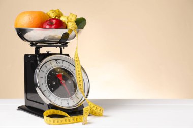 Mutfak terazisinde bir kase mezura şerit ve bej arka planda beyaz ahşap masa üzerindeki ürünler. Metin için boşluk