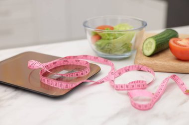 Mutfak terazileri, mezura ve salata beyaz masa içinde, yakın plan.