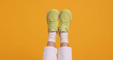 Turuncu arka planda şık ayakkabılar giyen kadın, yakın plan.