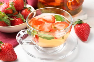 Aromatik çilekli meyve çayı ve beyaz masada nane şekeri, yakın plan.